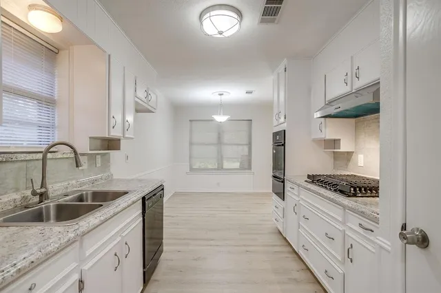 a kitchen with granite countertop a sink stove and cabinets