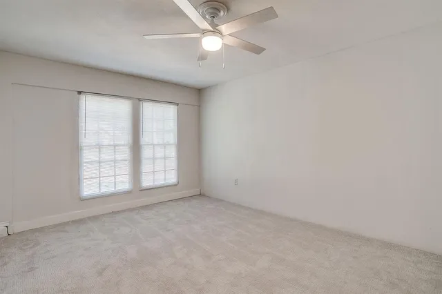 an empty room with a window and a ceiling fan