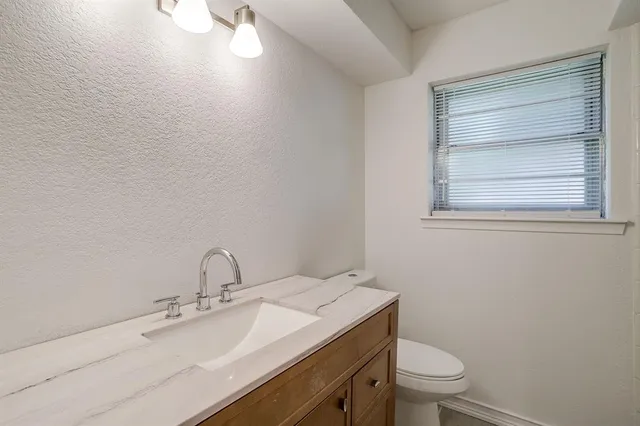 a bathroom with a granite countertop toilet a sink and mirror