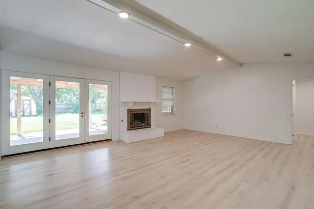 an empty room with wooden floor and fireplace