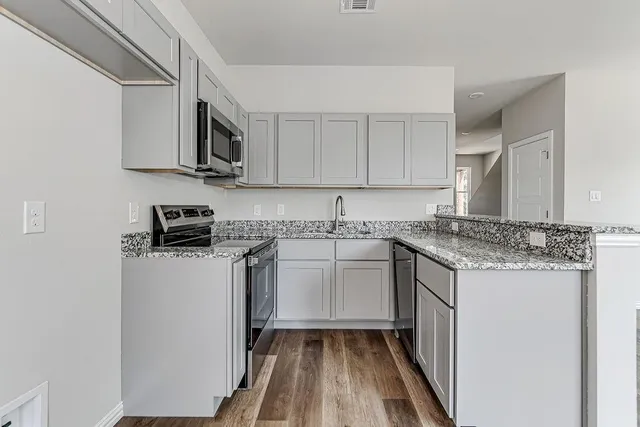 a kitchen with stainless steel appliances granite countertop a stove a sink and a microwave