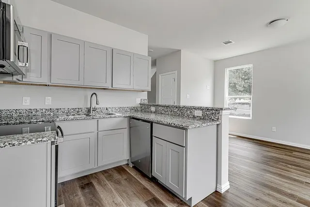 a kitchen with stainless steel appliances granite countertop a sink stove and cabinets