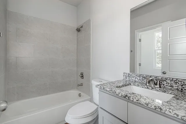 a bathroom with a granite countertop sink a toilet and bathtub
