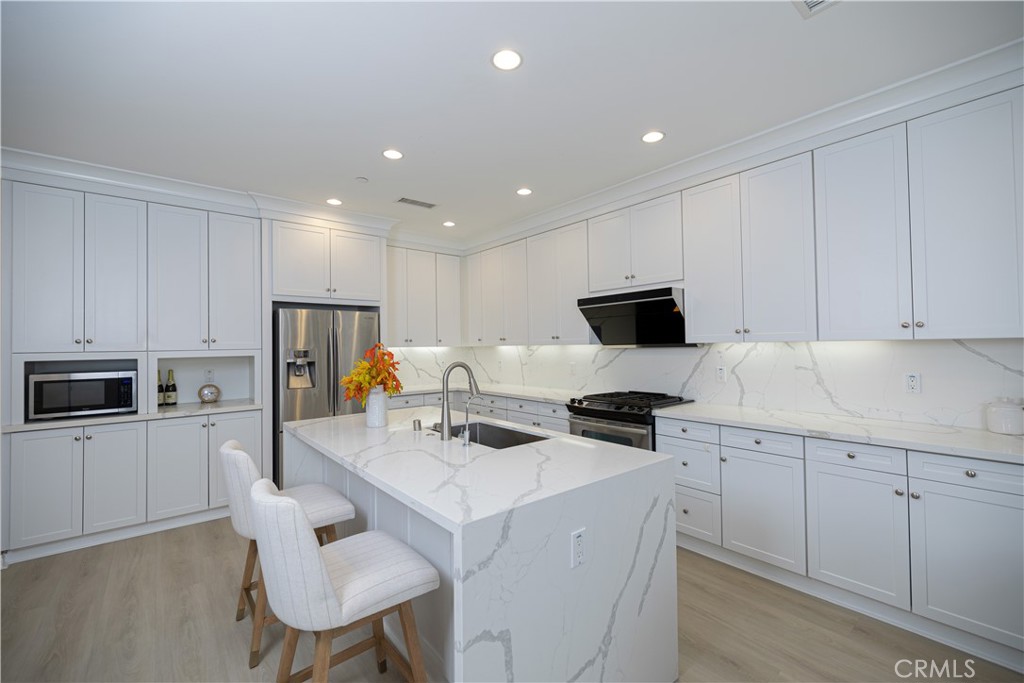 107 Overbrook Irvine, CA 92620 - Photo 37 of 47 a kitchen that has a lot of white cabinets and stainless steel appliances