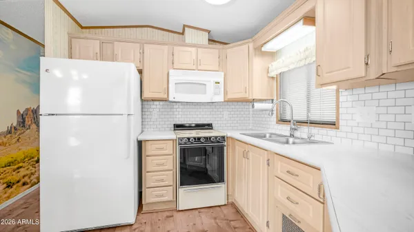 a kitchen with stainless steel appliances a refrigerator a stove a dining table and chairs with wooden floor