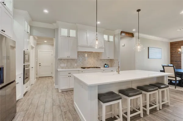 a kitchen with a dining table chairs appliances and cabinets