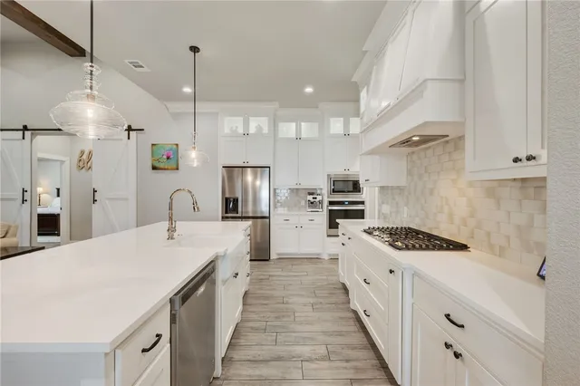 a kitchen with stainless steel appliances kitchen island granite countertop a sink and a refrigerator