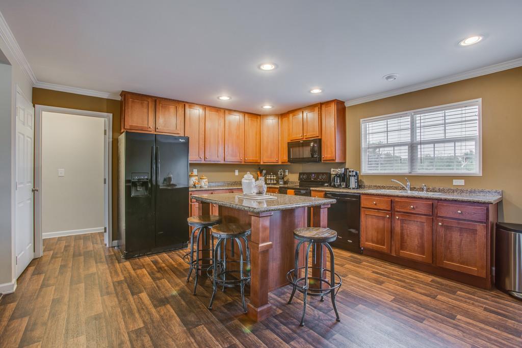 1142 Wrights Mill Road Spring Hill, TN 37174 - Photo 1 of 30 a kitchen with kitchen island granite countertop wooden floors and wooden cabinets