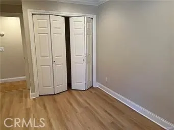 an empty room with wooden floor and closet area