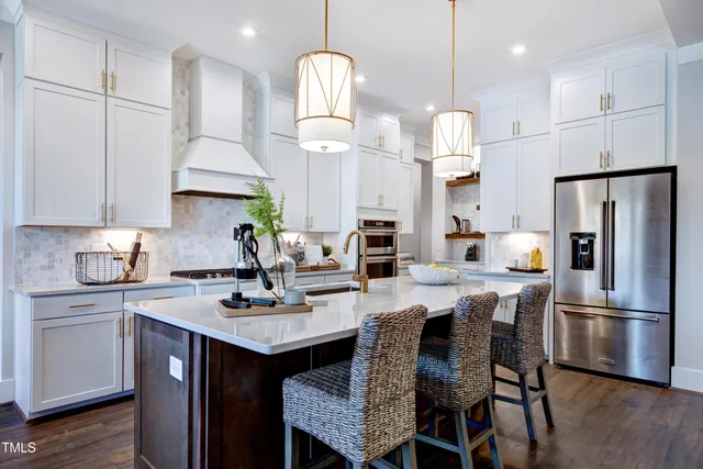 a kitchen with stainless steel appliances granite countertop a sink a stove a refrigerator and a dining table with wooden floor