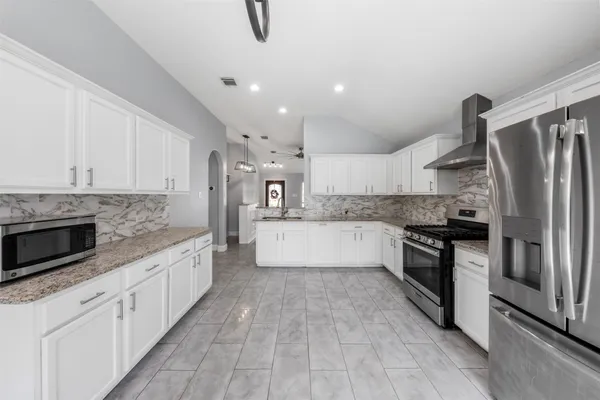 a large kitchen with stainless steel appliances granite countertop a stove a sink and a refrigerator