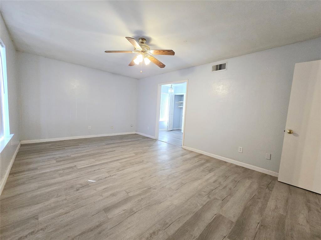 902 Spring Valley Plaza, Unit A Richardson, TX 75080 - Photo 3 of 11 an empty room with wooden floor fan and windows
