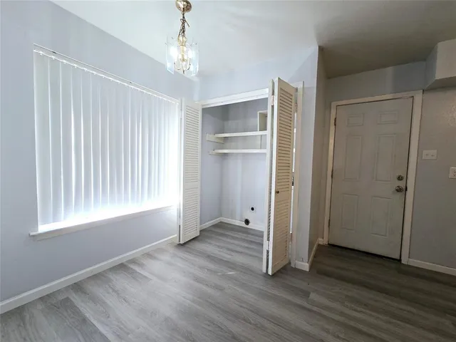 an empty room with wooden floor cabinet and windows