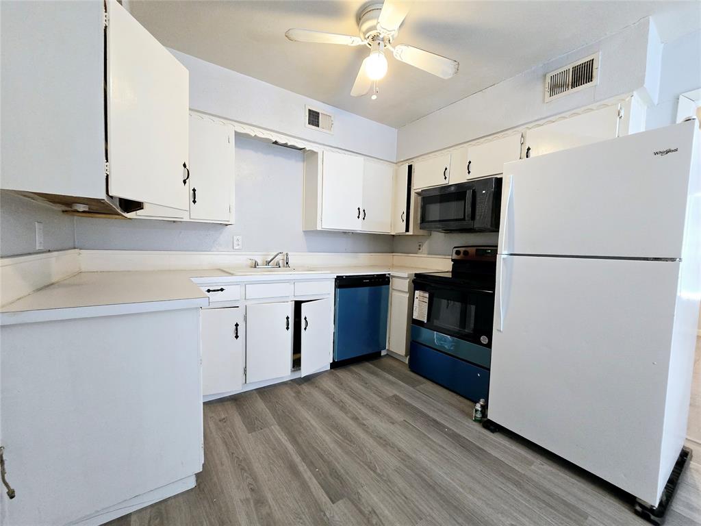 902 Spring Valley Plaza, Unit A Richardson, TX 75080 - Photo 7 of 11 a kitchen with stainless steel appliances granite countertop a refrigerator a stove top oven a sink and dishwasher with wooden floor