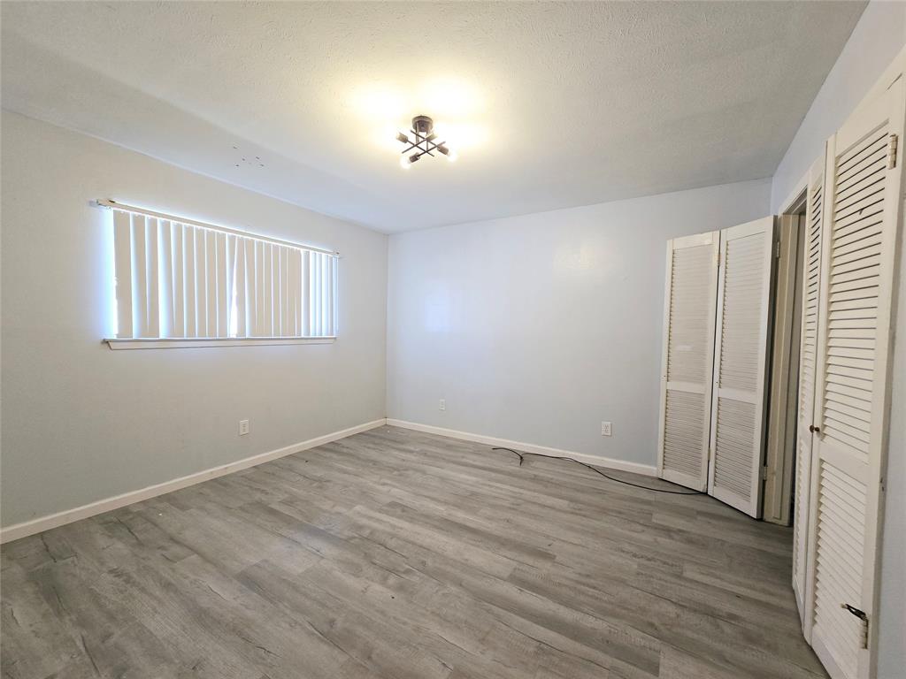 902 Spring Valley Plaza, Unit A Richardson, TX 75080 - Photo 8 of 11 a view of an empty room with wooden floor and a window
