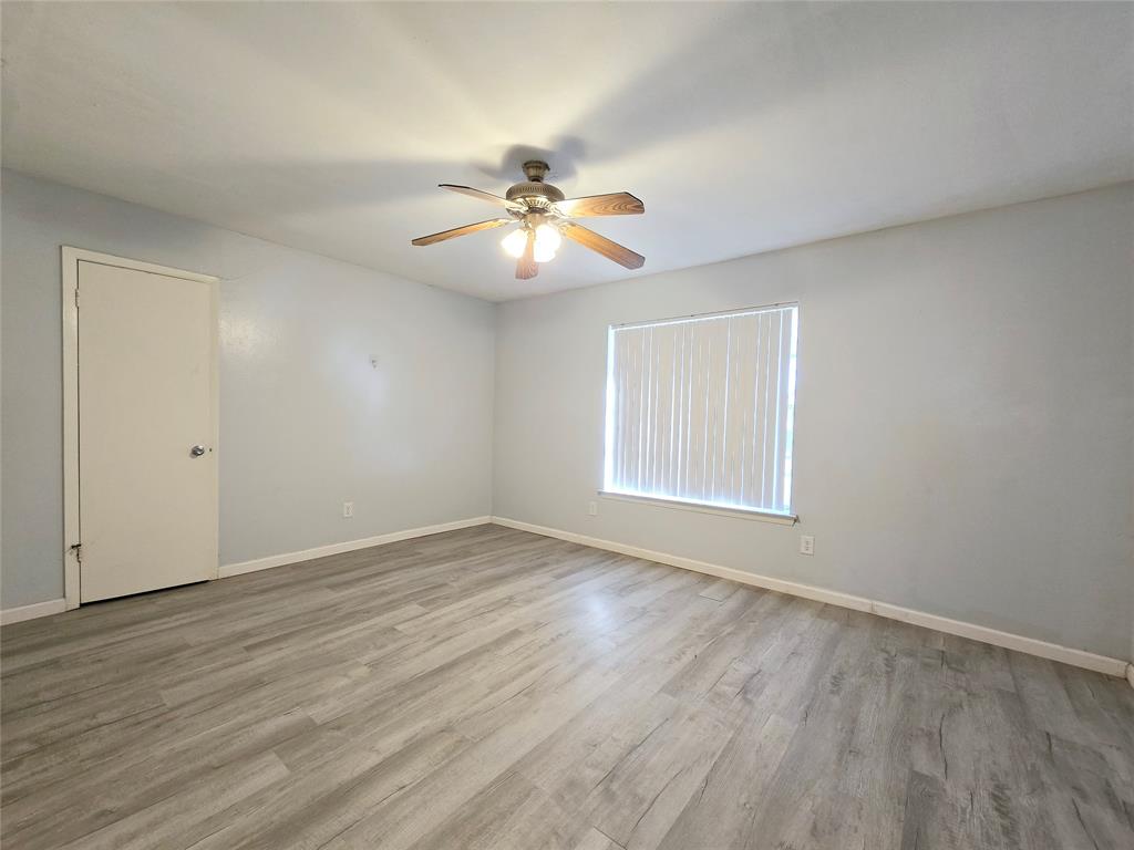 902 Spring Valley Plaza, Unit A Richardson, TX 75080 - Photo 9 of 11 a view of empty room with wooden floor and fan