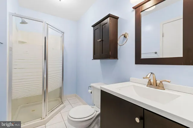 a bathroom with a toilet a sink a glass door a mirror a vanity and shower