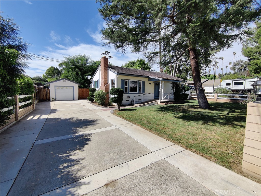 a front view of a house with garden and trees