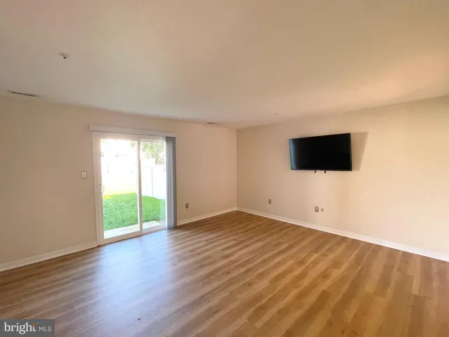 a view of an empty room with wooden floor and windows
