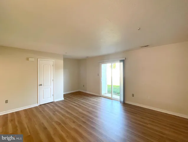 a view of an empty room with wooden floor and window