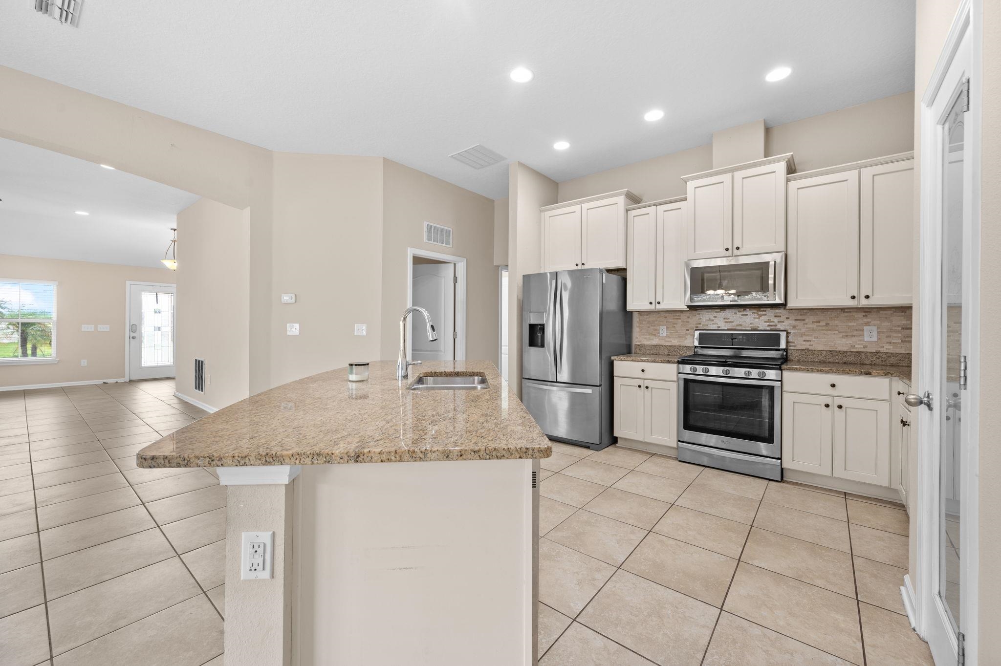 509 Deer Crossing Road St. Augustine, FL 32086 - Photo 12 of 54 a kitchen with stainless steel appliances granite countertop a sink a stove a refrigerator and a refrigerator