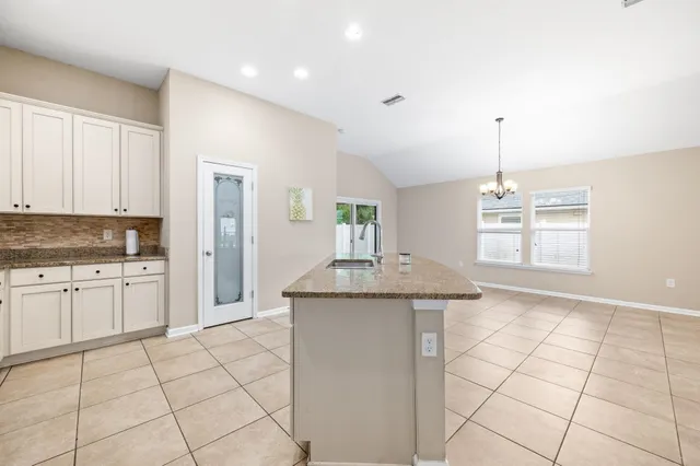 a kitchen with kitchen island granite countertop a sink and a stove top oven