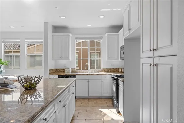 a kitchen with granite countertop a sink stove and cabinets
