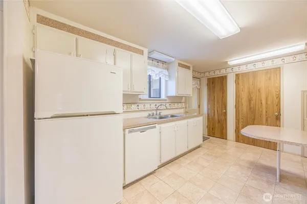 a large white kitchen with white cabinets and refrigerator