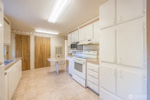 a kitchen with white cabinets and white appliances