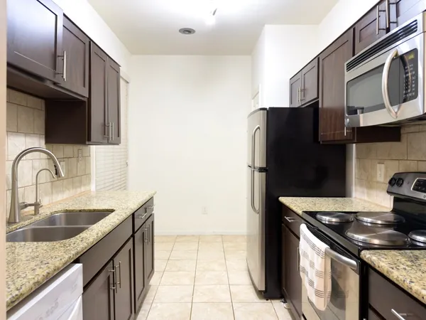 a kitchen with granite countertop a refrigerator and a sink