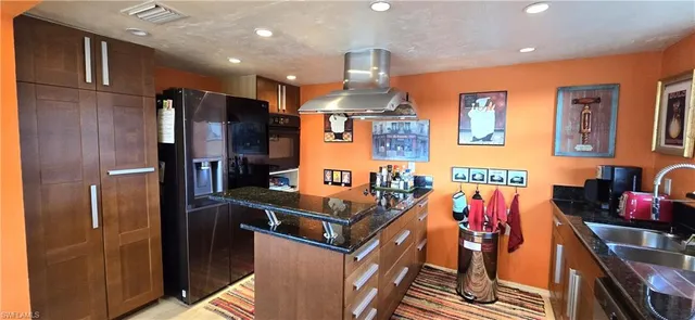 a kitchen with stainless steel appliances kitchen island granite countertop a refrigerator and a stove