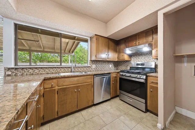 a kitchen with granite countertop a sink and a stove top oven