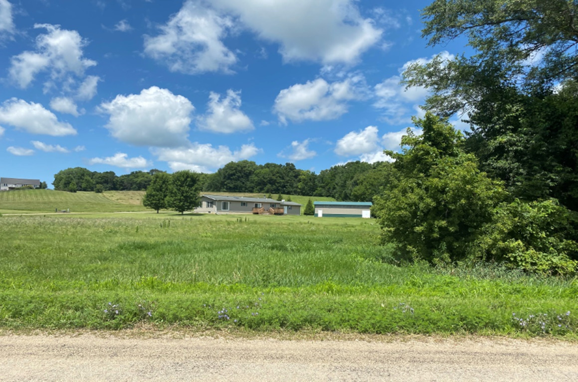 a view of a green field with wooden fence