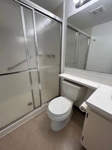 a white toilet sitting next to a shower