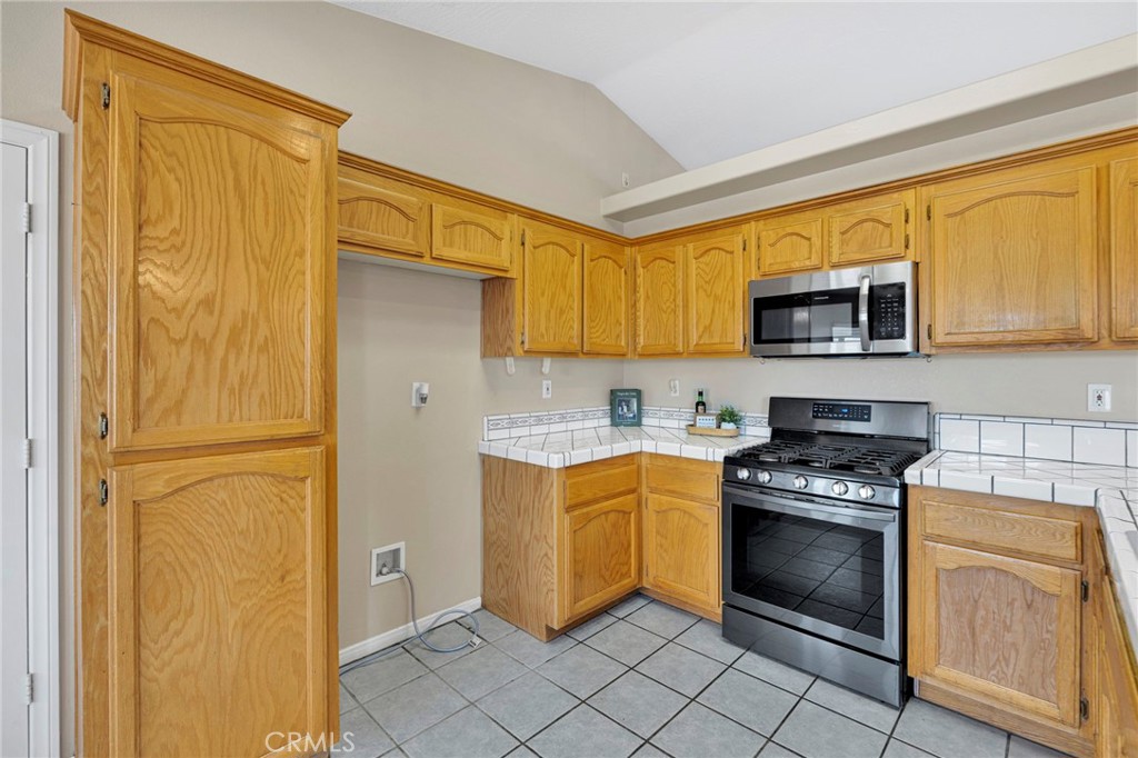 6271 Smoke Tree Road Phelan, CA 92371 - Photo 6 of 28 Kitchen with tile counters and wood cabinets with pantry cabinet