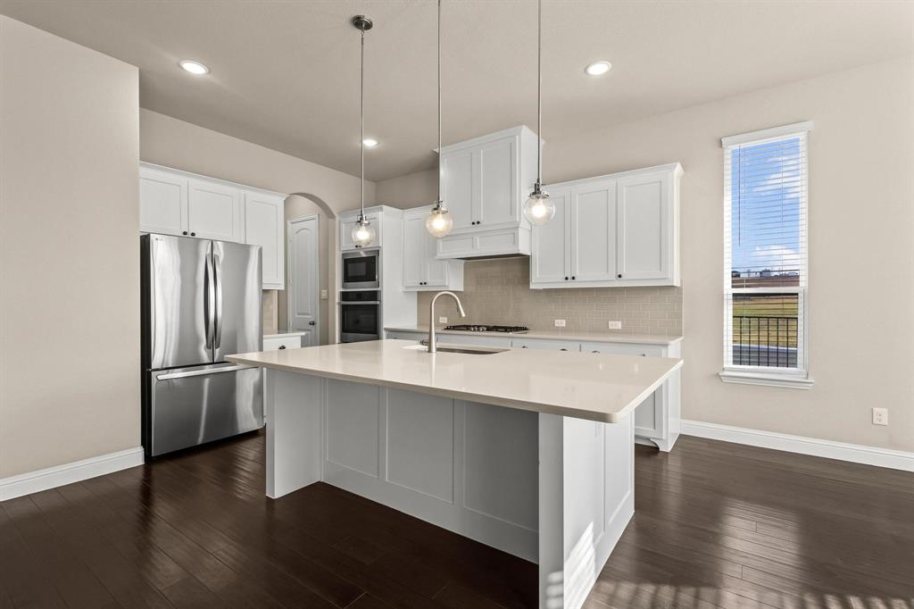 4001 Gentle Creek Lane Nevada, TX 75173 - Photo 12 of 40 a kitchen with stainless steel appliances granite countertop a refrigerator a sink dishwasher a stove and white cabinets with wooden floor
