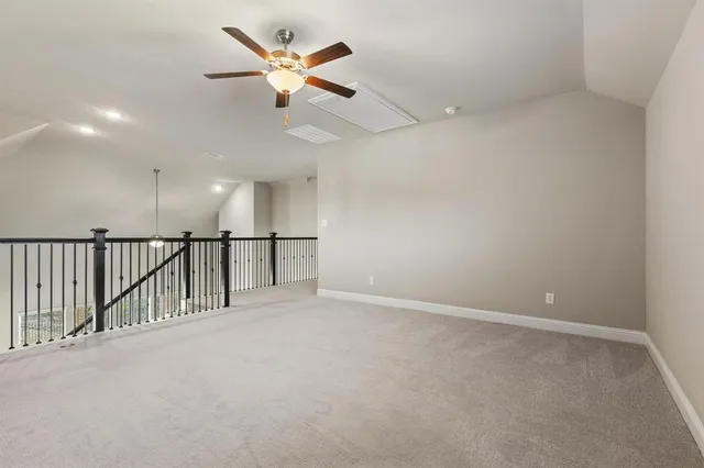 an empty room with ceiling fan and windows