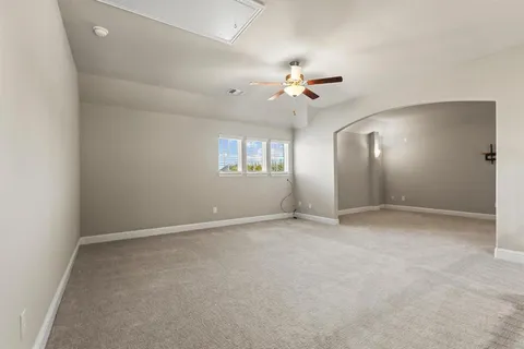 an empty room with chandelier fan and windows