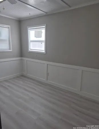 an empty room with wooden floor and windows