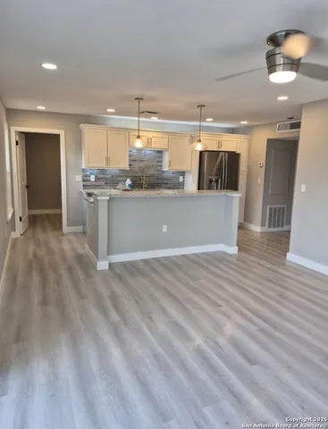 a open kitchen with a sink dishwasher a stove and white cabinets with wooden floor