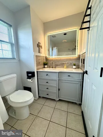 a bathroom with a granite countertop toilet a sink a mirror and a window
