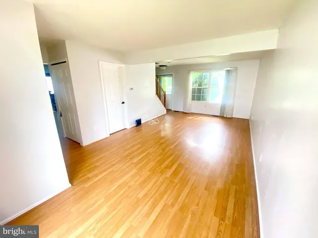a view of a big room with wooden floor and windows