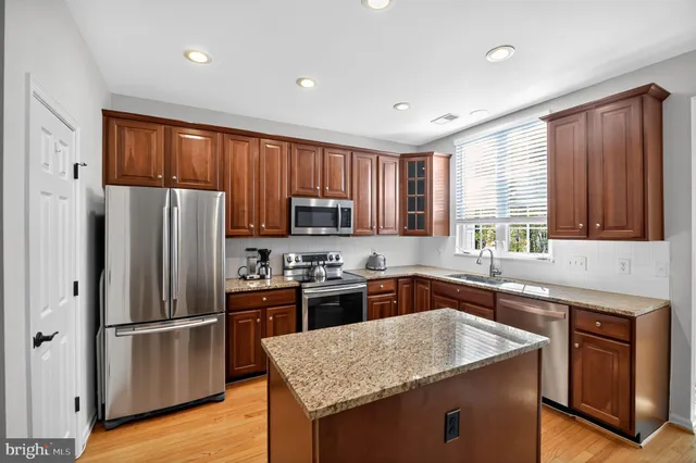 a kitchen with granite countertop stainless steel appliances a refrigerator stove top oven and sink