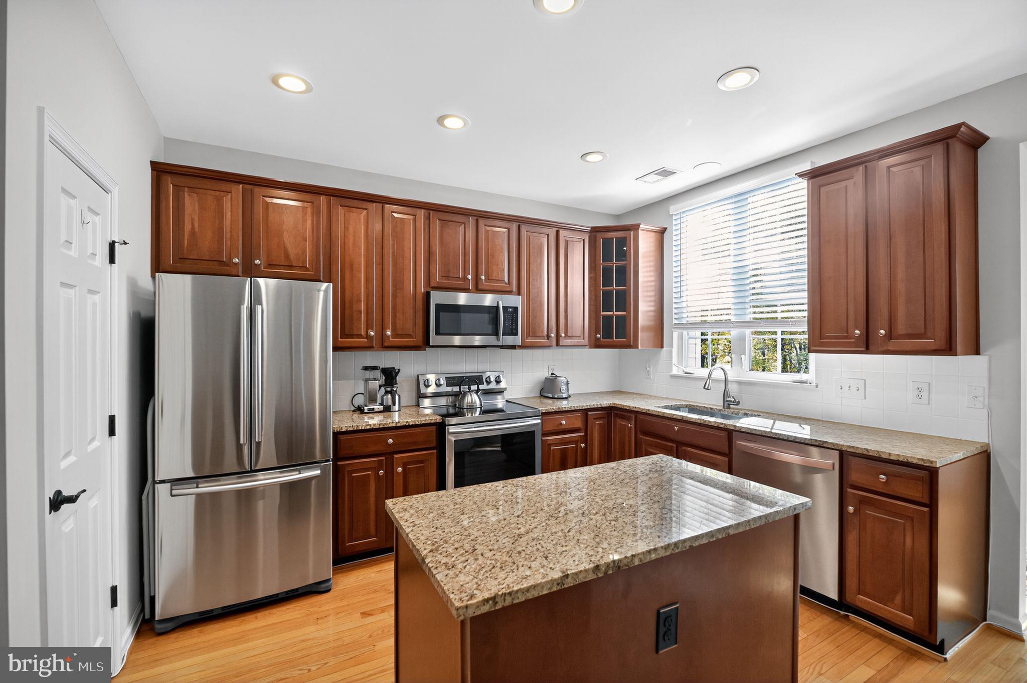a kitchen with granite countertop stainless steel appliances a refrigerator stove top oven and sink