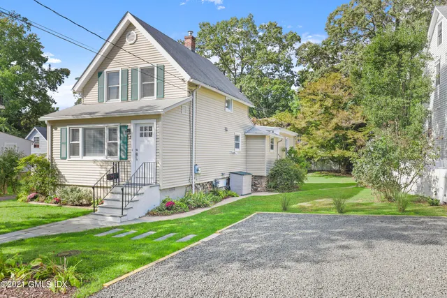 a front view of a house with a yard and trees