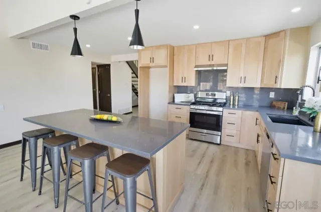 a kitchen with stainless steel appliances kitchen island granite countertop a table chairs and a refrigerator