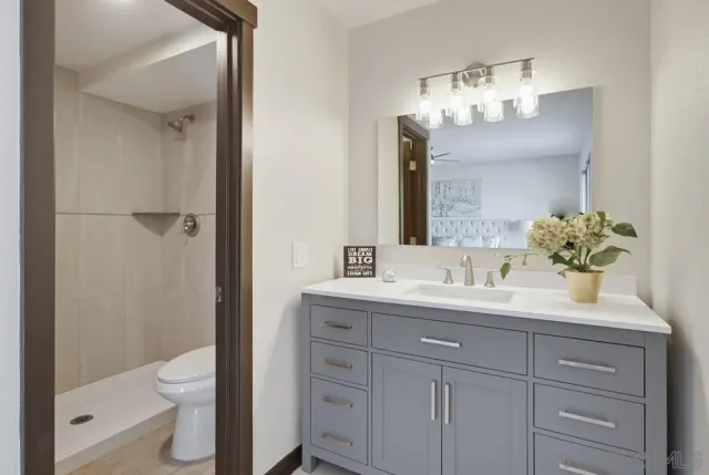 a bathroom with a granite countertop sink a toilet and a mirror