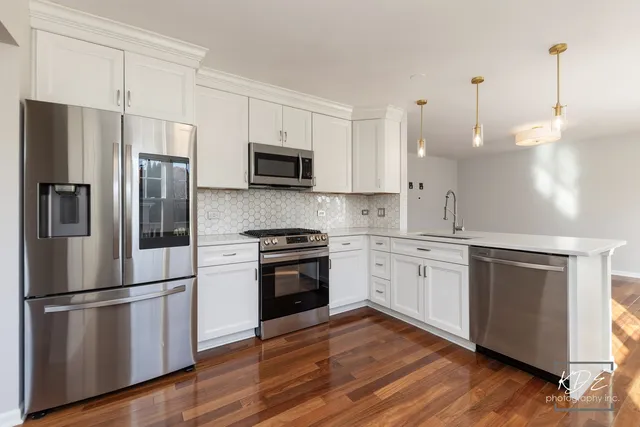 a kitchen with stainless steel appliances and wooden floor