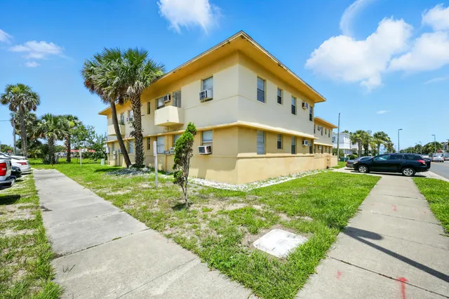 a front view of a building with a garden and plants