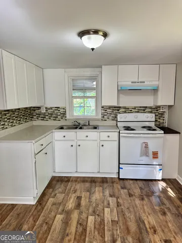 a kitchen with granite countertop a stove sink and cabinets
